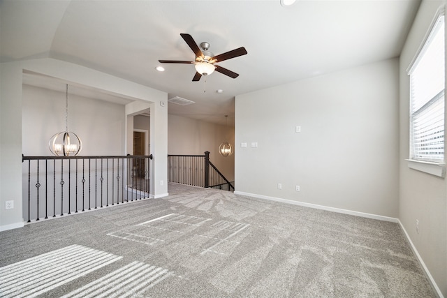 carpeted empty room featuring lofted ceiling and ceiling fan with notable chandelier