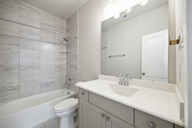 full bathroom with tile patterned flooring, tiled shower / bath, toilet, and vanity