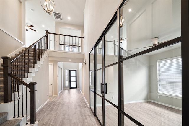 entrance foyer featuring french doors, light hardwood / wood-style floors, a healthy amount of sunlight, and a high ceiling