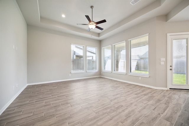 unfurnished room with light hardwood / wood-style floors, ceiling fan, and a raised ceiling