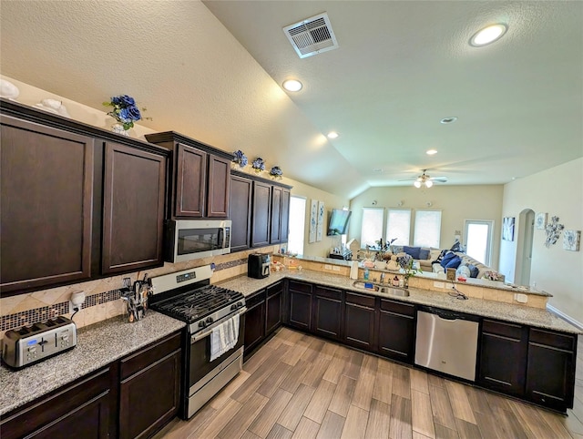 kitchen with light hardwood / wood-style floors, sink, kitchen peninsula, appliances with stainless steel finishes, and lofted ceiling