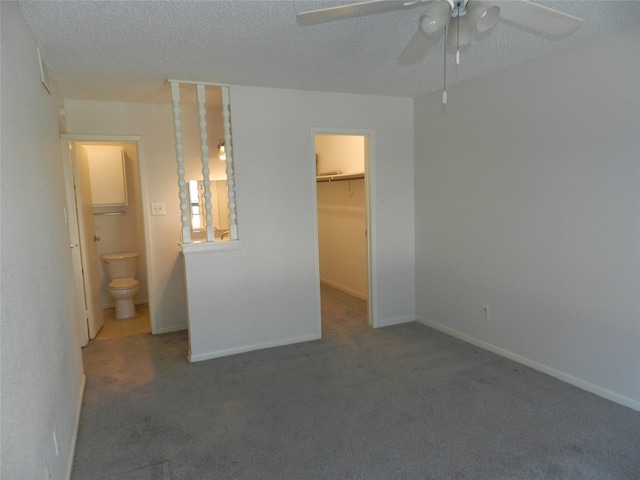 unfurnished bedroom with ceiling fan, a textured ceiling, a spacious closet, a closet, and carpet floors