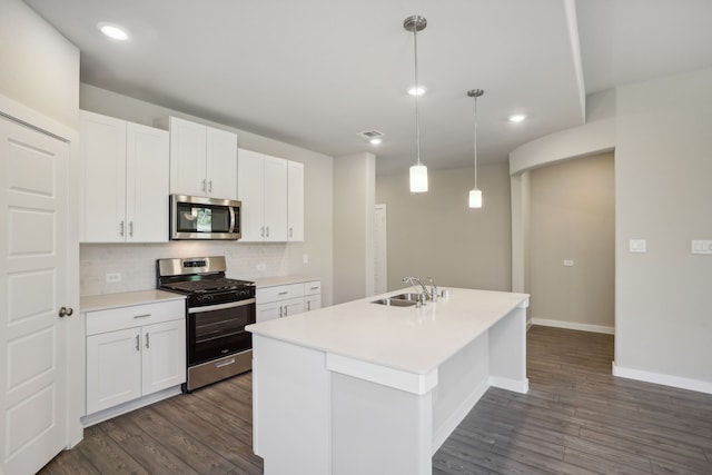 kitchen with an island with sink, appliances with stainless steel finishes, white cabinets, and decorative light fixtures