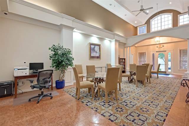 dining room with decorative columns, ceiling fan, and a towering ceiling