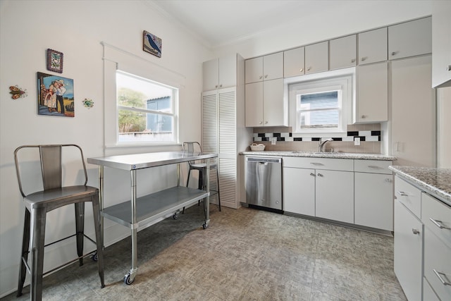 kitchen with stainless steel dishwasher, crown molding, backsplash, and sink