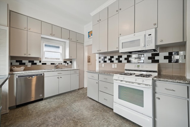 kitchen featuring white appliances, light stone countertops, sink, and backsplash