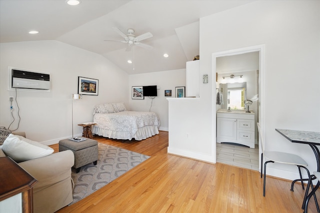 bedroom featuring light hardwood / wood-style floors, lofted ceiling, ceiling fan, and ensuite bath