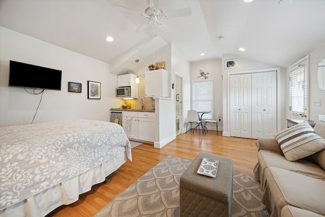 bedroom featuring a closet, light wood-type flooring, vaulted ceiling, and ceiling fan