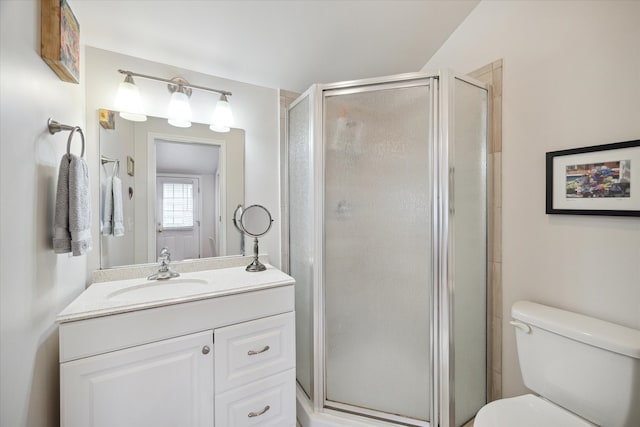 bathroom with a shower with door, vanity, and toilet