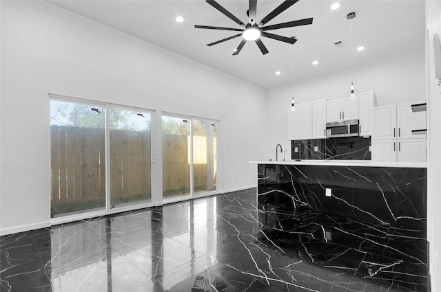 kitchen featuring white cabinets, ceiling fan, sink, and a wealth of natural light