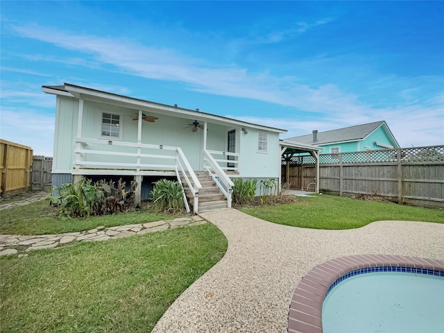 back of property featuring a swimming pool, ceiling fan, and a yard