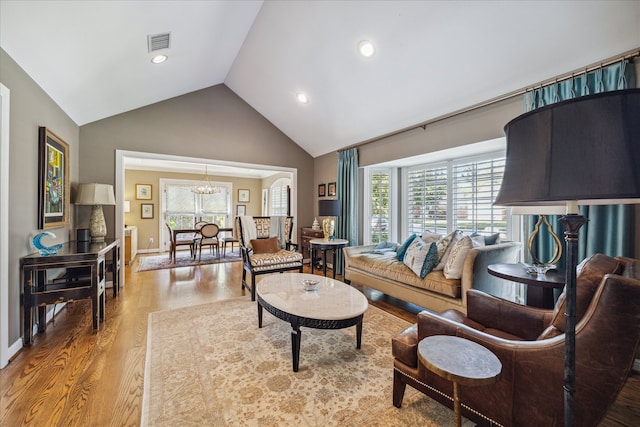 living room with a chandelier, wood-type flooring, and vaulted ceiling