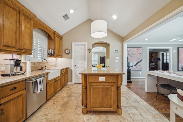 kitchen featuring dishwasher, sink, pendant lighting, lofted ceiling, and light wood-type flooring