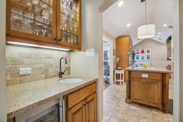 bar featuring light stone countertops, backsplash, vaulted ceiling, sink, and pendant lighting