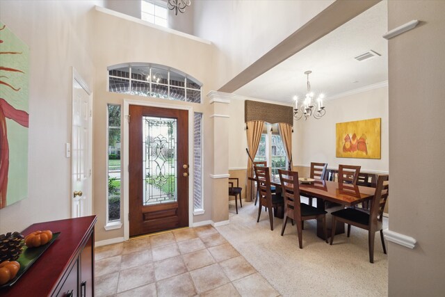 foyer featuring a high ceiling, an inviting chandelier, light carpet, and crown molding