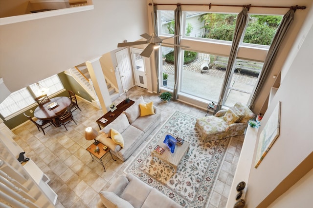 living room with a high ceiling, ceiling fan, and a healthy amount of sunlight