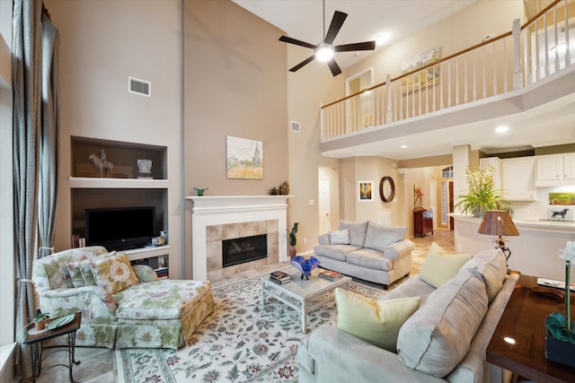 living room featuring a high ceiling, a tiled fireplace, and ceiling fan