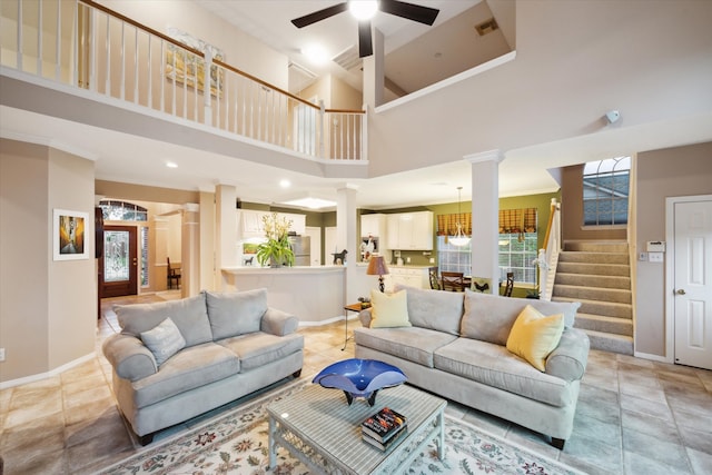 living room with ornate columns, ceiling fan, and a high ceiling