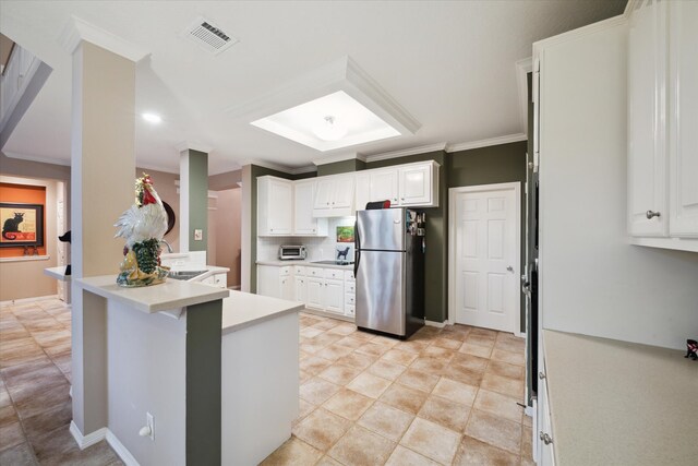 kitchen with ornamental molding, stainless steel refrigerator, sink, white cabinets, and kitchen peninsula