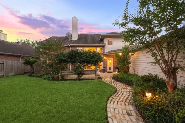 back house at dusk with a yard and a patio area