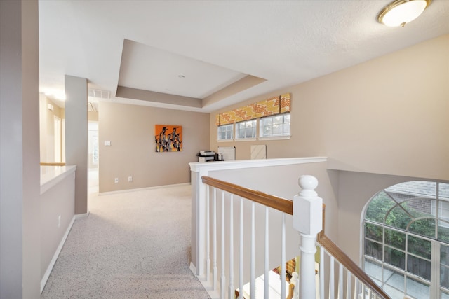 hallway with carpet floors and a tray ceiling