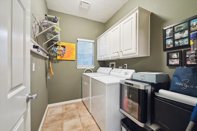 washroom with washing machine and dryer, cabinets, a textured ceiling, and light tile patterned flooring