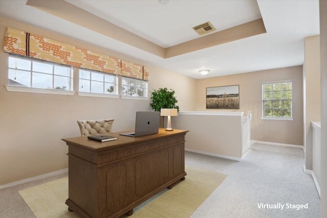 carpeted home office featuring a tray ceiling