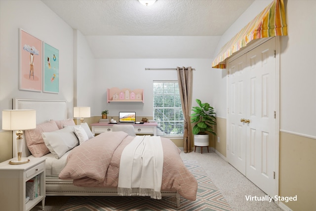 carpeted bedroom with lofted ceiling and a textured ceiling