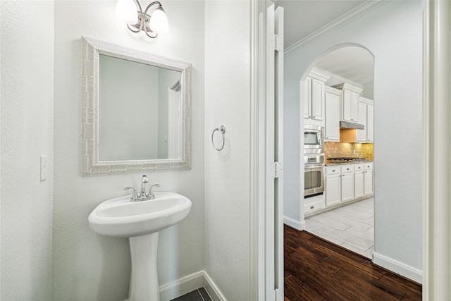 bathroom with wood-type flooring, ornamental molding, and tasteful backsplash