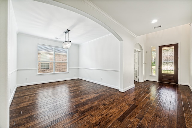 foyer entrance featuring dark hardwood / wood-style floors, ornamental molding, and a notable chandelier