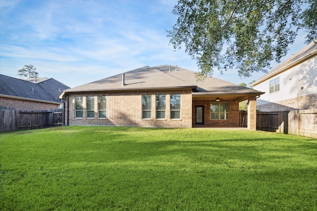 back of house with ceiling fan and a yard