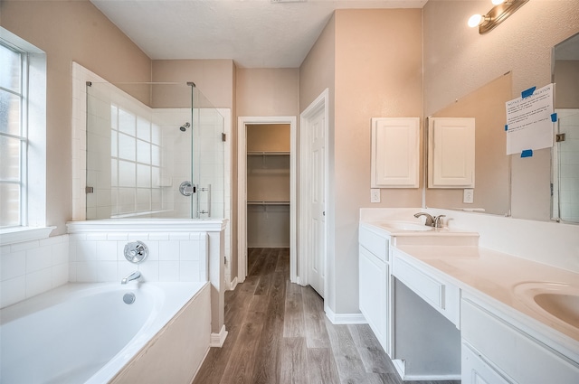 bathroom featuring wood-type flooring, a textured ceiling, vanity, and plus walk in shower