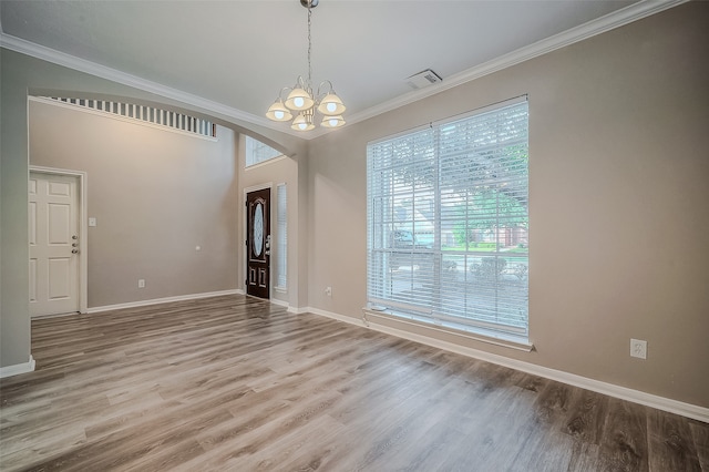 unfurnished room with hardwood / wood-style floors, an inviting chandelier, and ornamental molding