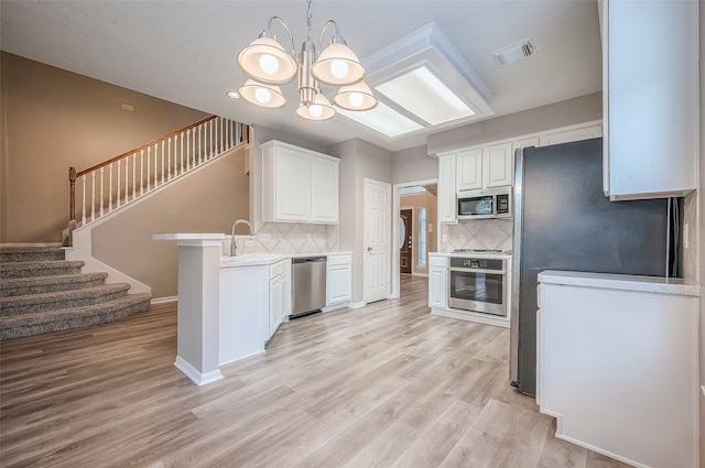 kitchen with stainless steel appliances, white cabinetry, backsplash, and light wood-type flooring