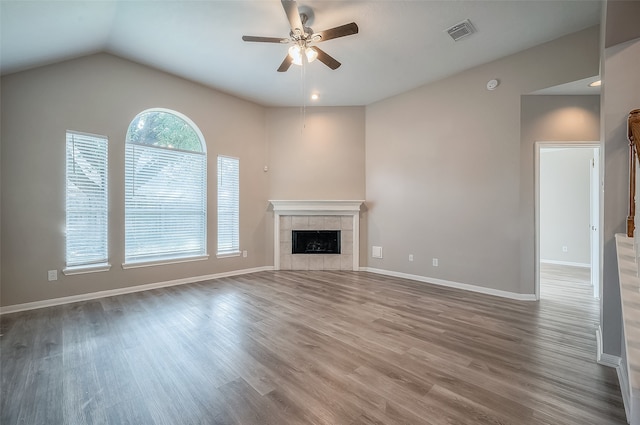 unfurnished living room featuring a tiled fireplace, wood-type flooring, ceiling fan, and vaulted ceiling