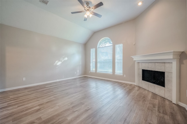 unfurnished living room featuring light hardwood / wood-style flooring, ceiling fan, a tile fireplace, and vaulted ceiling