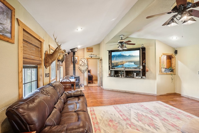 living room with hardwood / wood-style floors, lofted ceiling, a wood stove, and ceiling fan