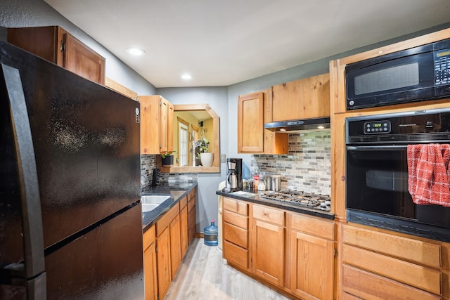 kitchen with black appliances, ventilation hood, backsplash, sink, and light hardwood / wood-style flooring