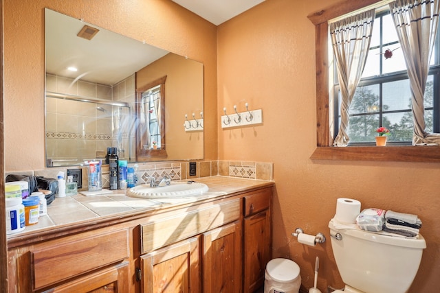 bathroom with an enclosed shower, vanity, tasteful backsplash, and toilet