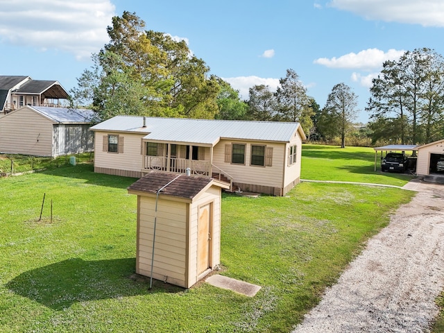 view of front of home featuring a storage unit, a front yard, and a carport