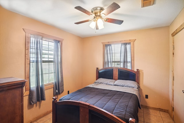 bedroom featuring multiple windows, light tile patterned floors, and ceiling fan