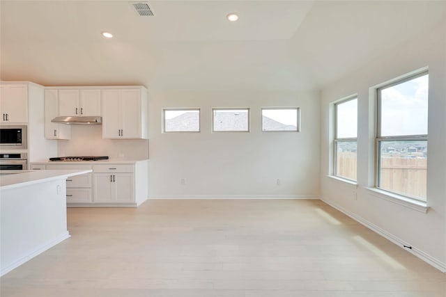 kitchen with built in microwave, white cabinetry, light hardwood / wood-style floors, and stainless steel oven