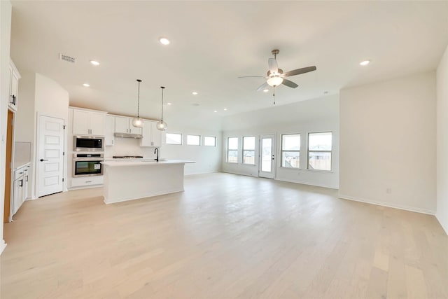 kitchen featuring ceiling fan, white cabinetry, stainless steel appliances, a center island with sink, and decorative light fixtures