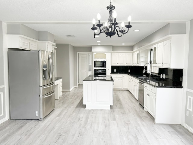 kitchen featuring stainless steel appliances, light hardwood / wood-style floors, sink, a center island, and white cabinets