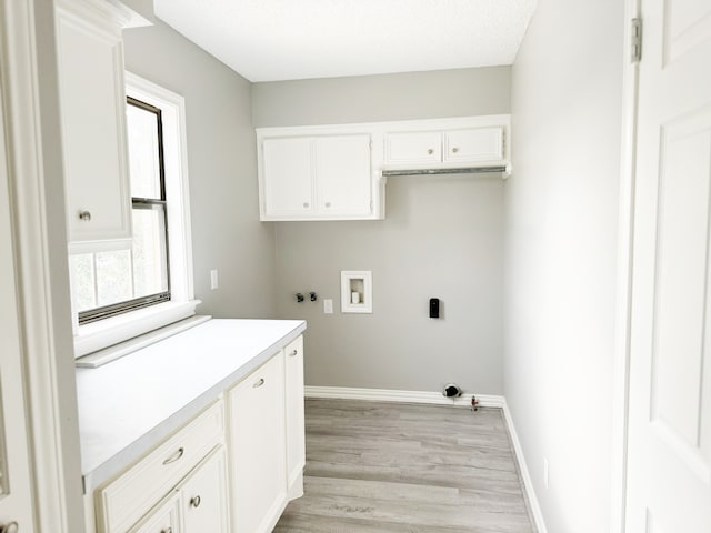 washroom with light wood-type flooring, cabinets, a healthy amount of sunlight, and washer hookup