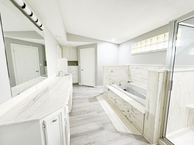 bathroom with a textured ceiling, wood-type flooring, vanity, separate shower and tub, and vaulted ceiling