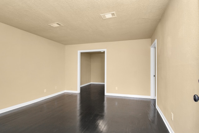 empty room featuring dark hardwood / wood-style floors and a textured ceiling