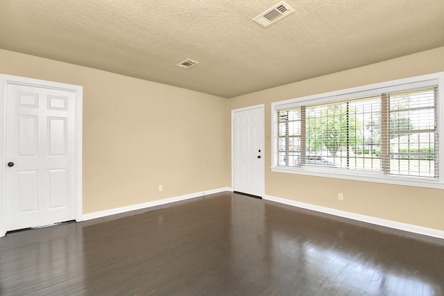 empty room with a textured ceiling and dark hardwood / wood-style floors