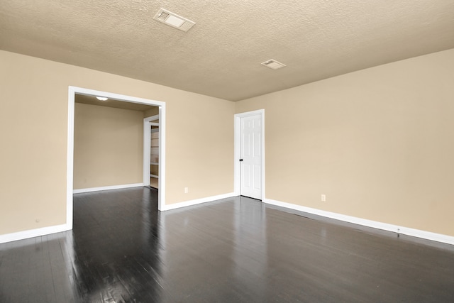 empty room with a textured ceiling and dark wood-type flooring