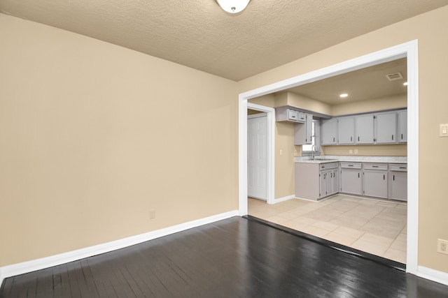 kitchen with gray cabinets, sink, light tile patterned flooring, and a textured ceiling